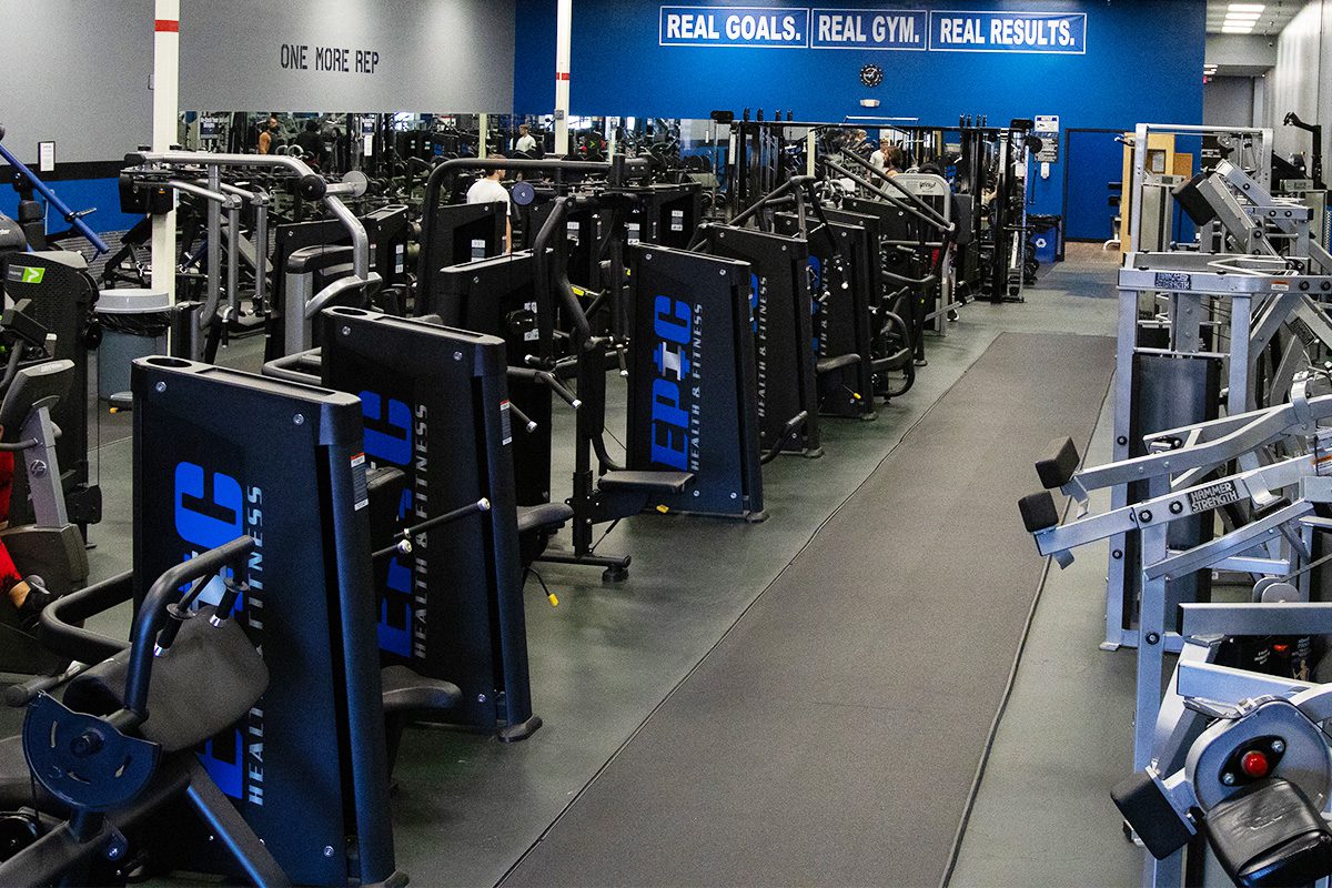 Spring Hill Epic Fitness strength training zone—premium weight machines, leg press stations, and chest press equipment in a spacious gym with motivational wall signs and mirrors.